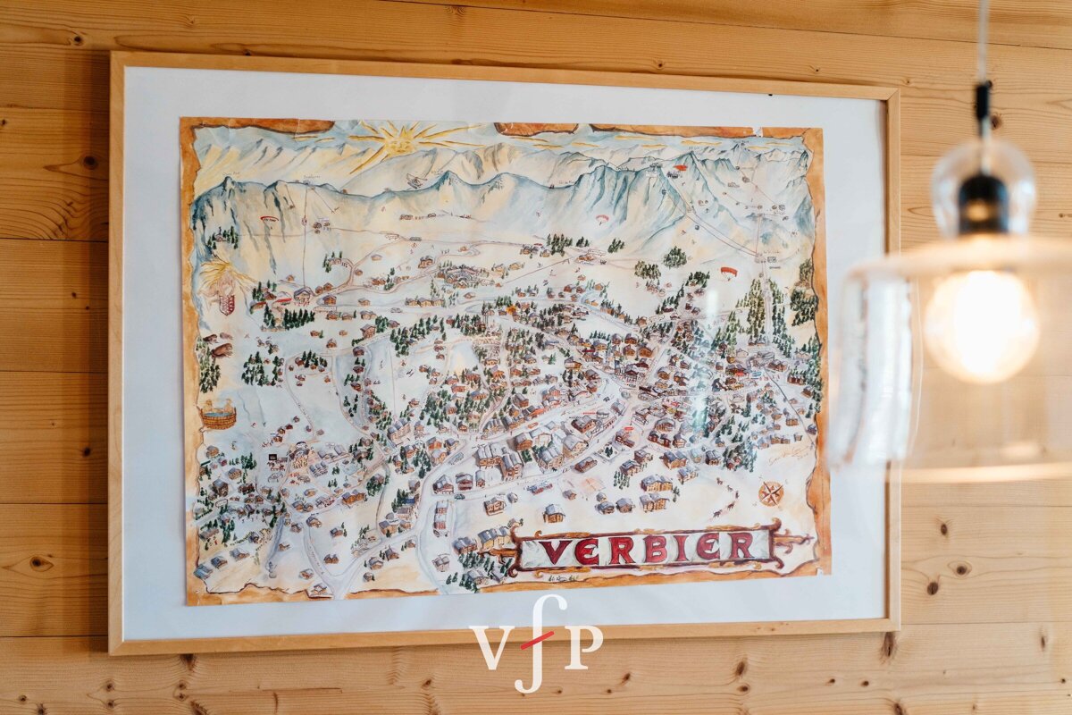 A framed map of verbier hangs on a wooden wall