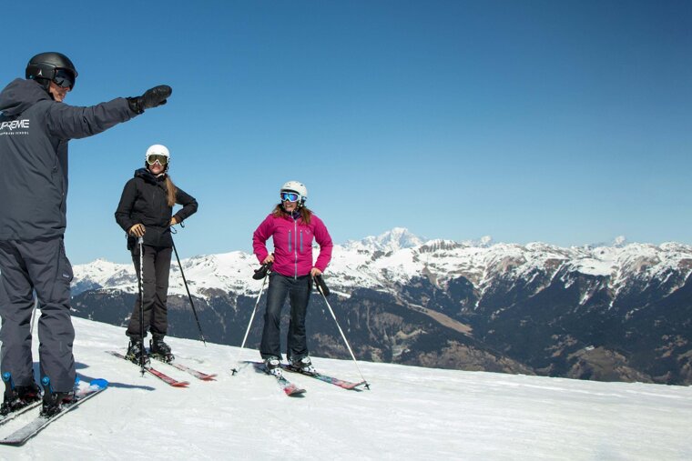 Skiers on a snowy slope with one wearing a jacket that says reve
