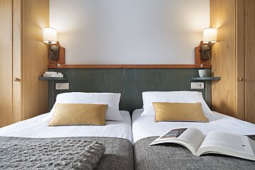 A hotel room with two beds and a book on the bed