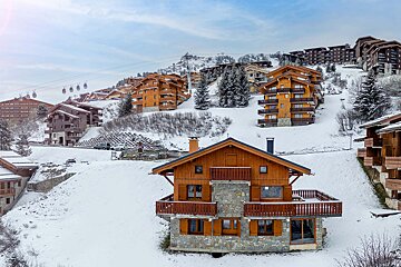 A snowy landscape with a ski resort in the background