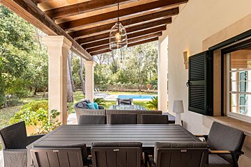 A table and chairs on a porch with a pool in the background