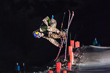 a skier grabbing his skis mid air