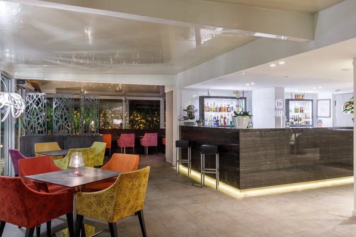 A bar in a restaurant with colorful chairs and tables