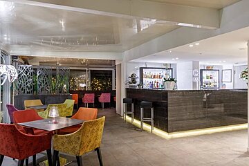 A bar in a restaurant with colorful chairs and tables