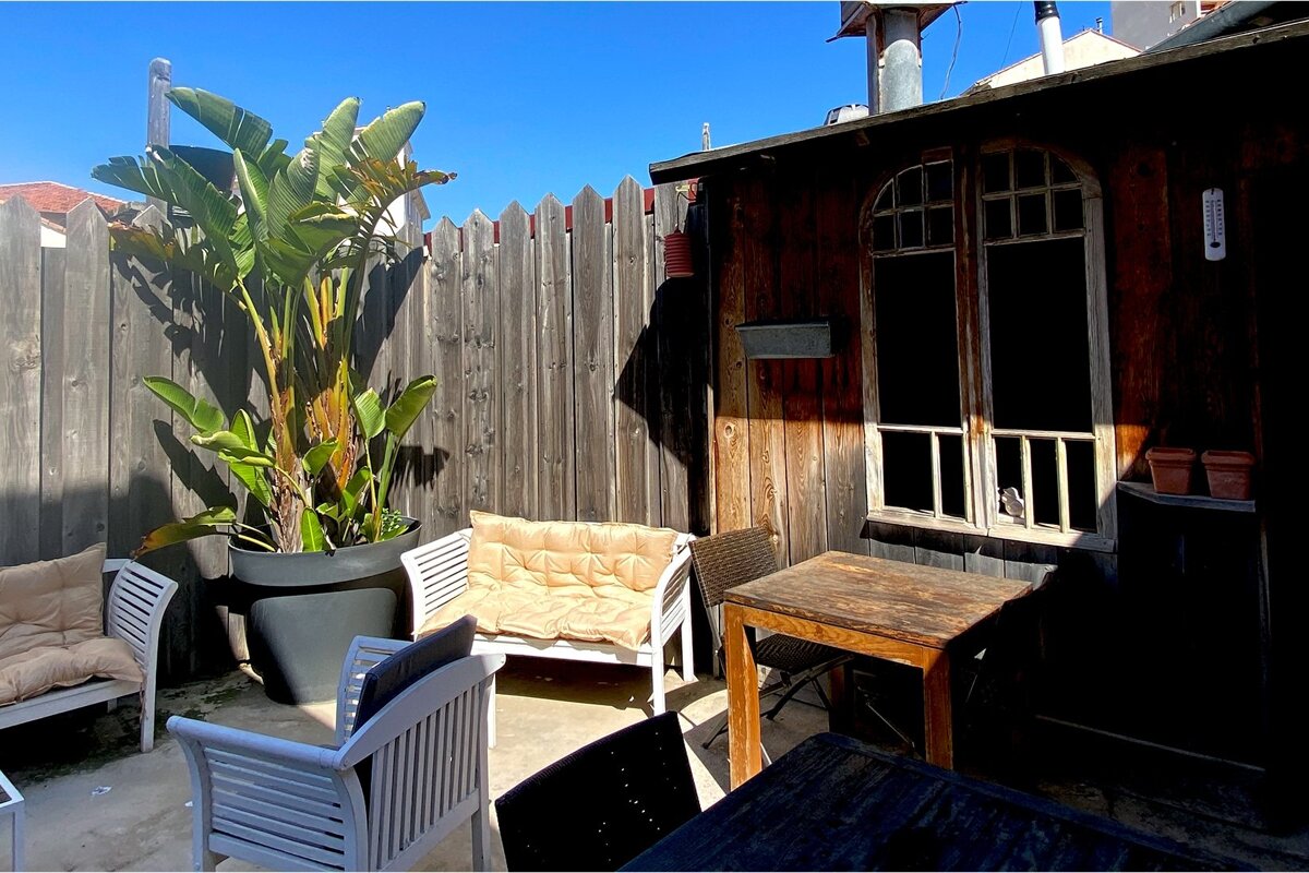 A wooden fence surrounds a patio area with a table and chairs