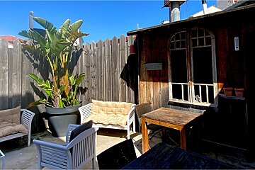 A wooden fence surrounds a patio area with a table and chairs