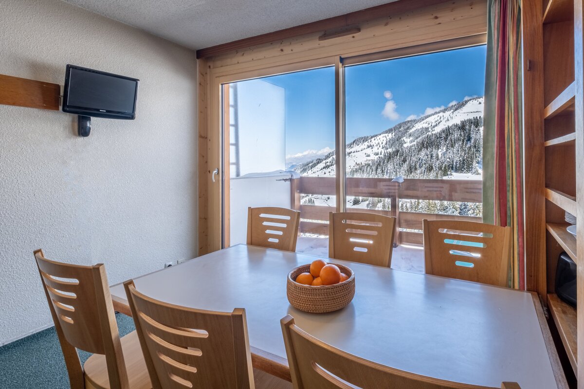 A dining room table with a bowl of oranges on it