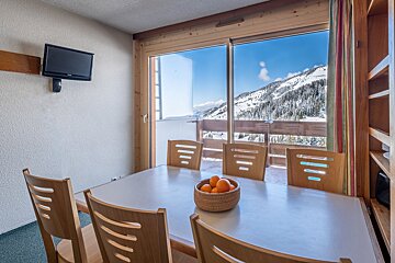 A dining room table with a bowl of oranges on it