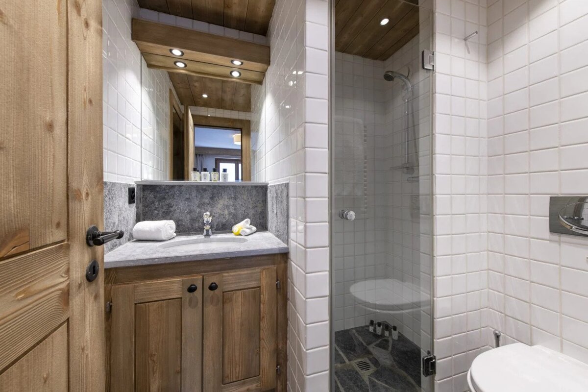 A bathroom with white tiles and a toilet