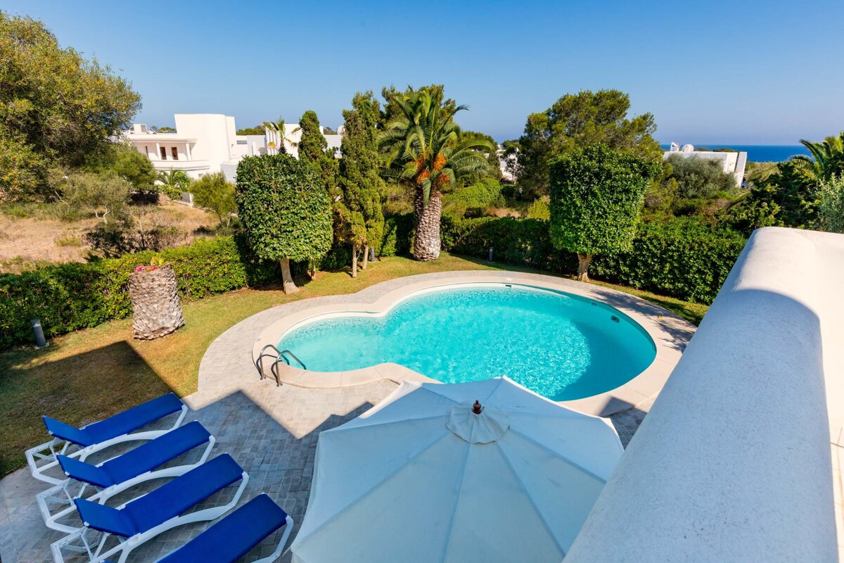 A white umbrella sits in front of a swimming pool