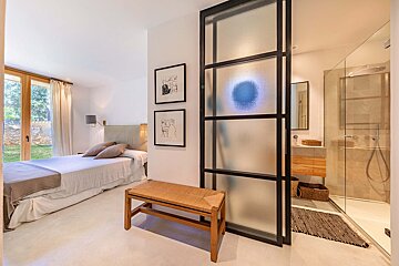 A bedroom with a large bed and a walk in shower