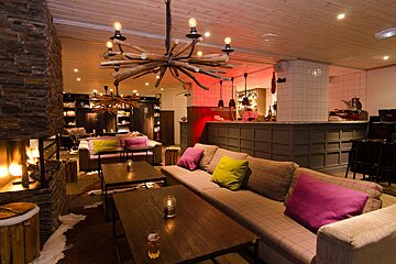 A couch with purple pillows sits in front of a fireplace