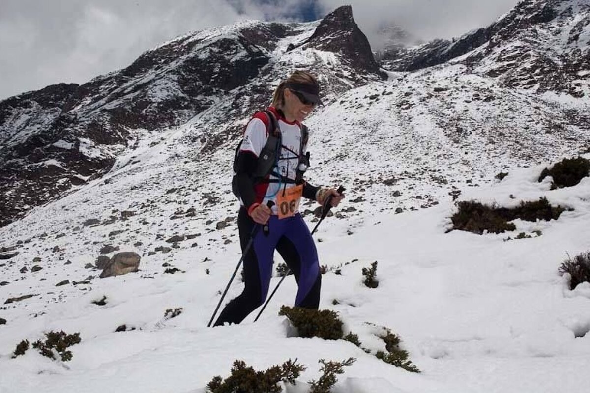 a trail runner with poles in the snow