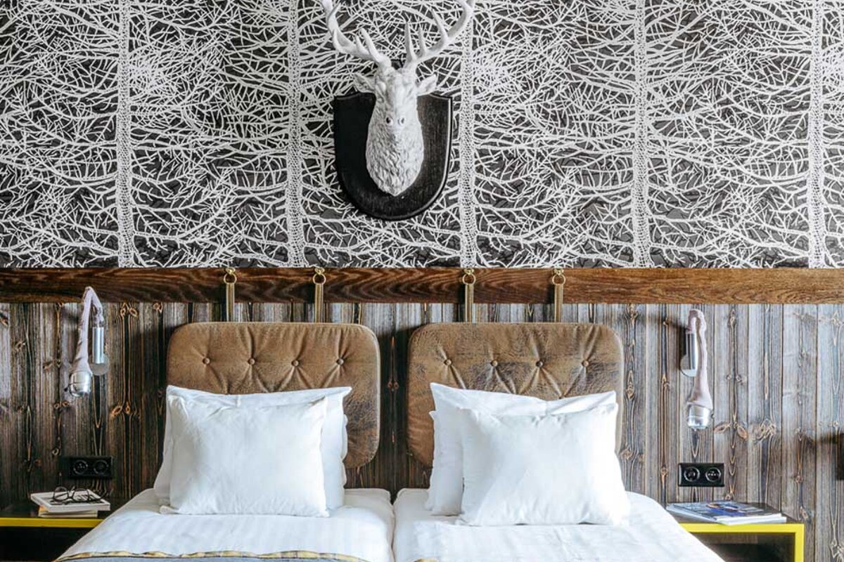 A bedroom with two beds and a deer head on the wall