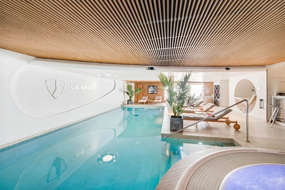 A large indoor swimming pool with le spa written on the wall
