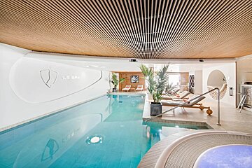 A large indoor swimming pool with le spa written on the wall