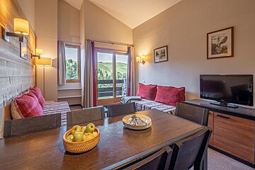 A living room with a dining table and a flat screen tv