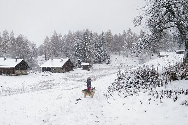 A hiker and a dog on a trail in the snow near Chamonix