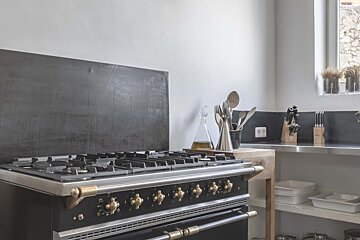 A black stove with gold knobs is in a kitchen