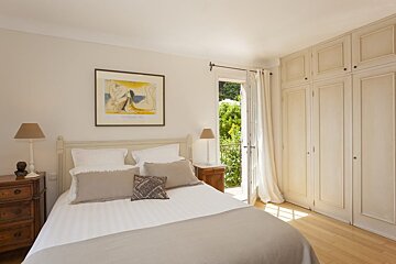 A bedroom with a bed and a picasso painting on the wall