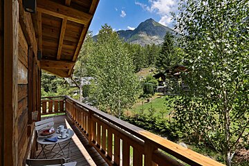A wooden balcony with a mountain in the background