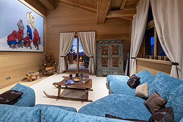 A living room with blue couches and a painting on the wall