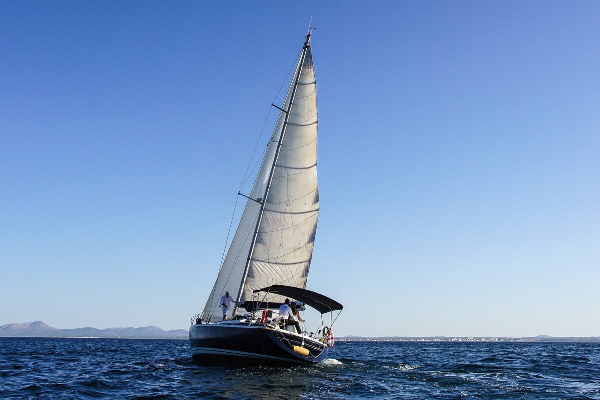 A sailboat in the ocean with a few people on it