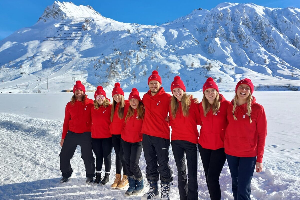 A group of people posing for a picture in front of a snowy mountain