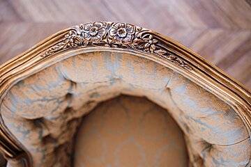 A close up of a chair with a gold frame