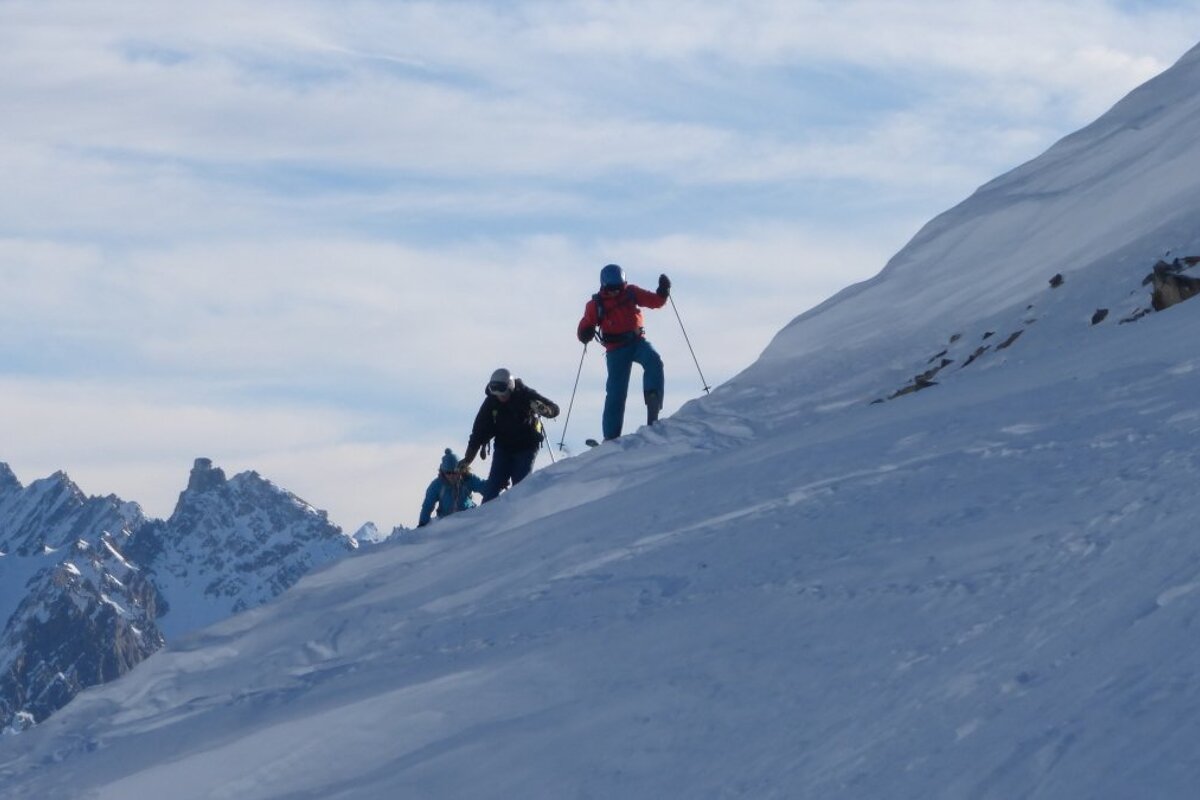 three skiers on a ridge