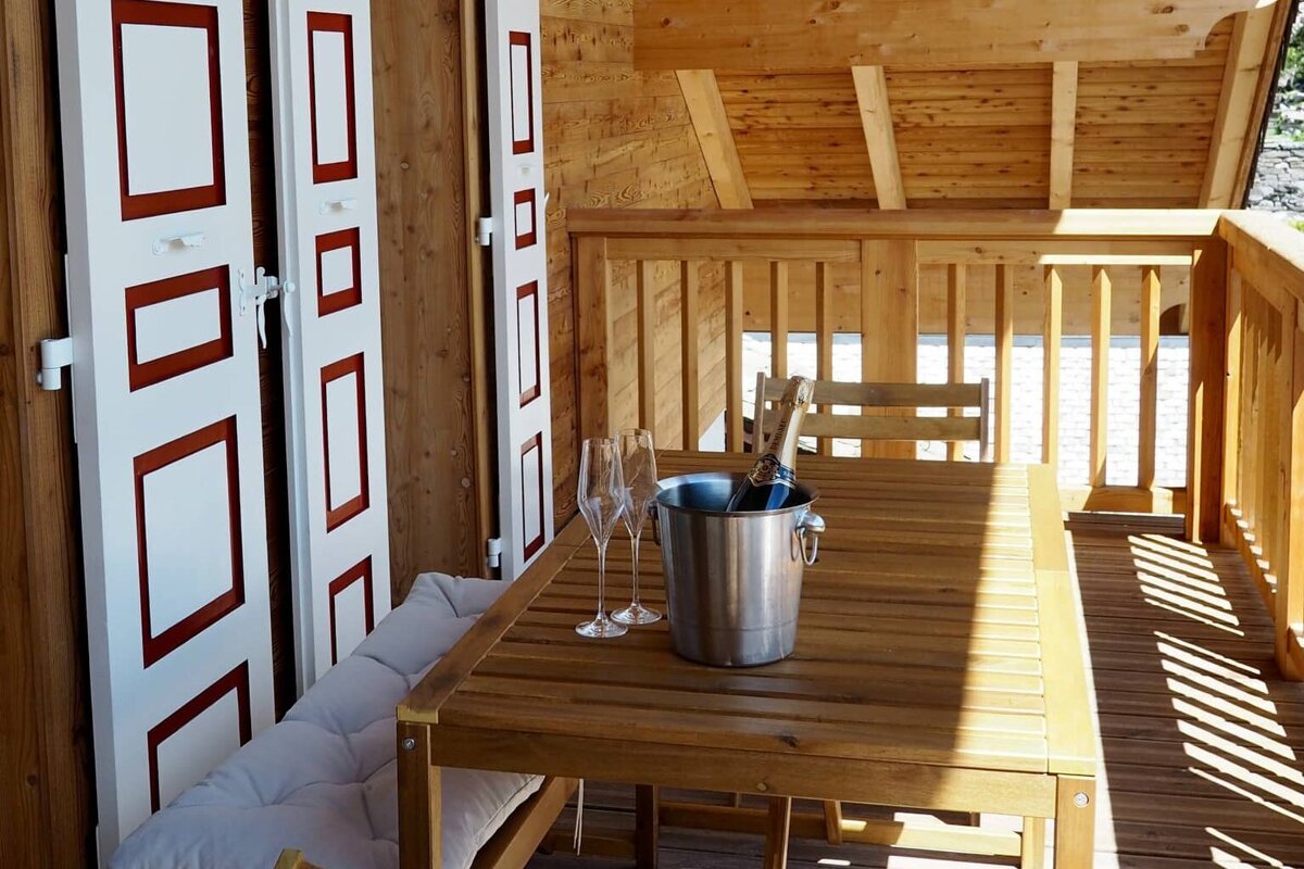 A wooden table with a bucket of champagne and two glasses on it