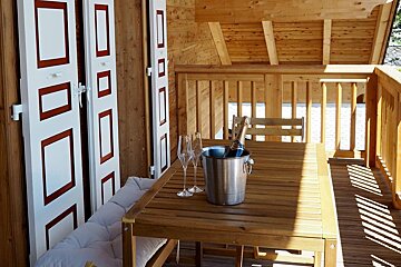 A wooden table with a bucket of champagne and two glasses on it