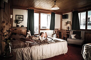 Two children are laying on a bed in a hotel room
