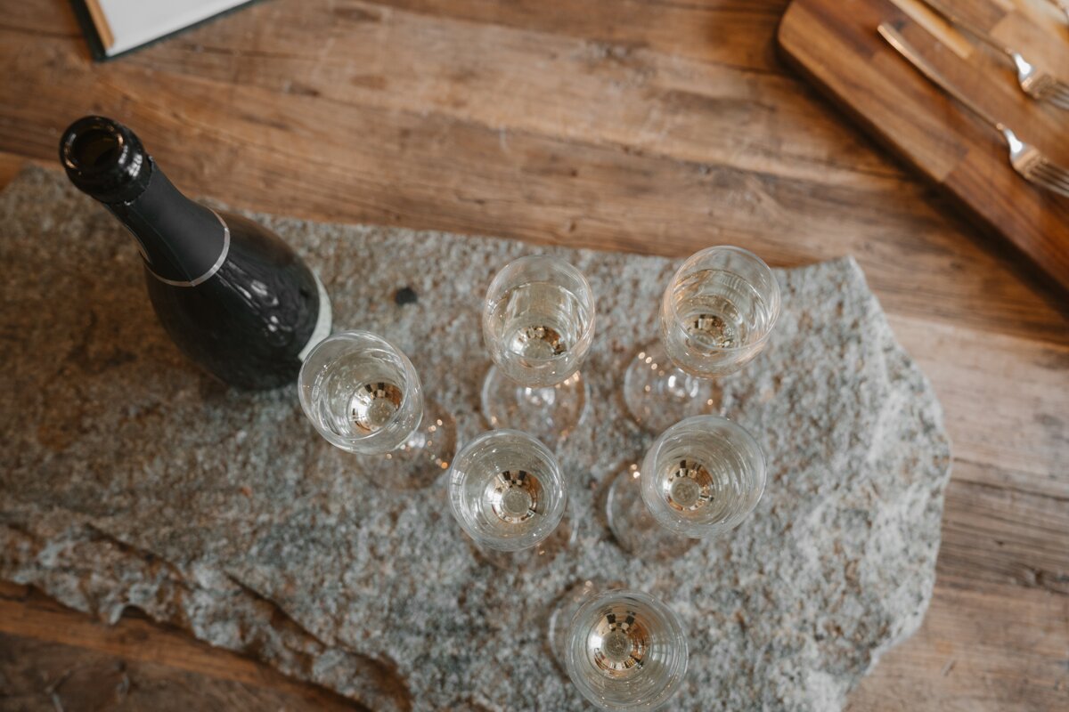 A bottle of champagne sits next to six empty glasses