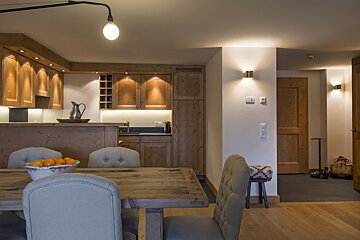 A bowl of oranges sits on a table in a kitchen
