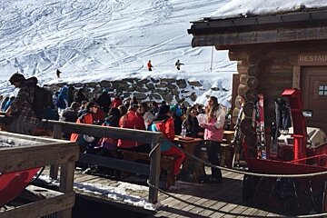 people sat on benches at a mountain restaurant