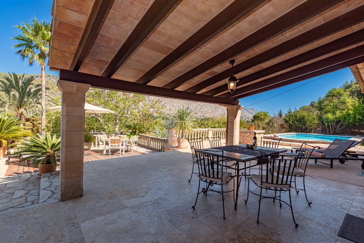 A patio with a table and chairs and a pool in the background