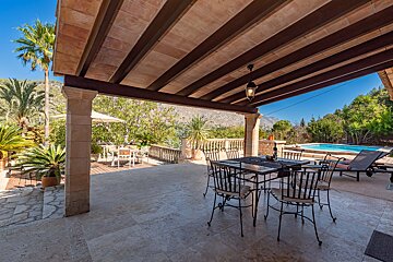 A patio with a table and chairs and a pool in the background