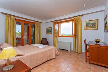 A bedroom with a large bed and a desk
