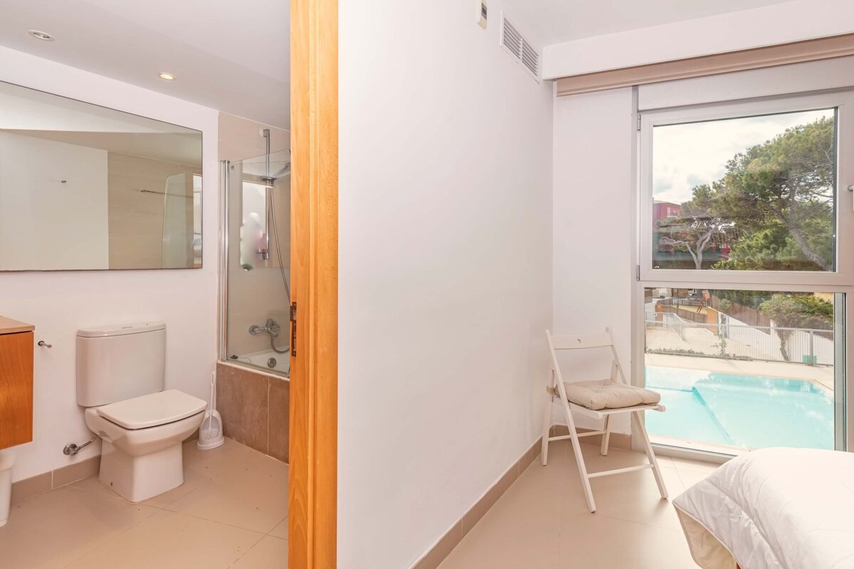 A bathroom with a toilet and a chair next to it