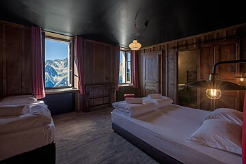A bedroom with two beds and a window with mountains in the background