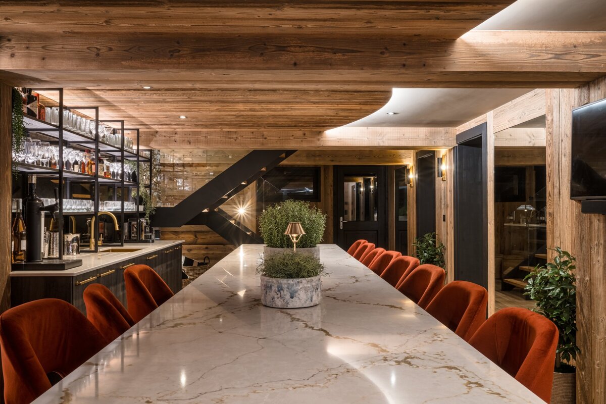 A long marble table with red chairs in a room