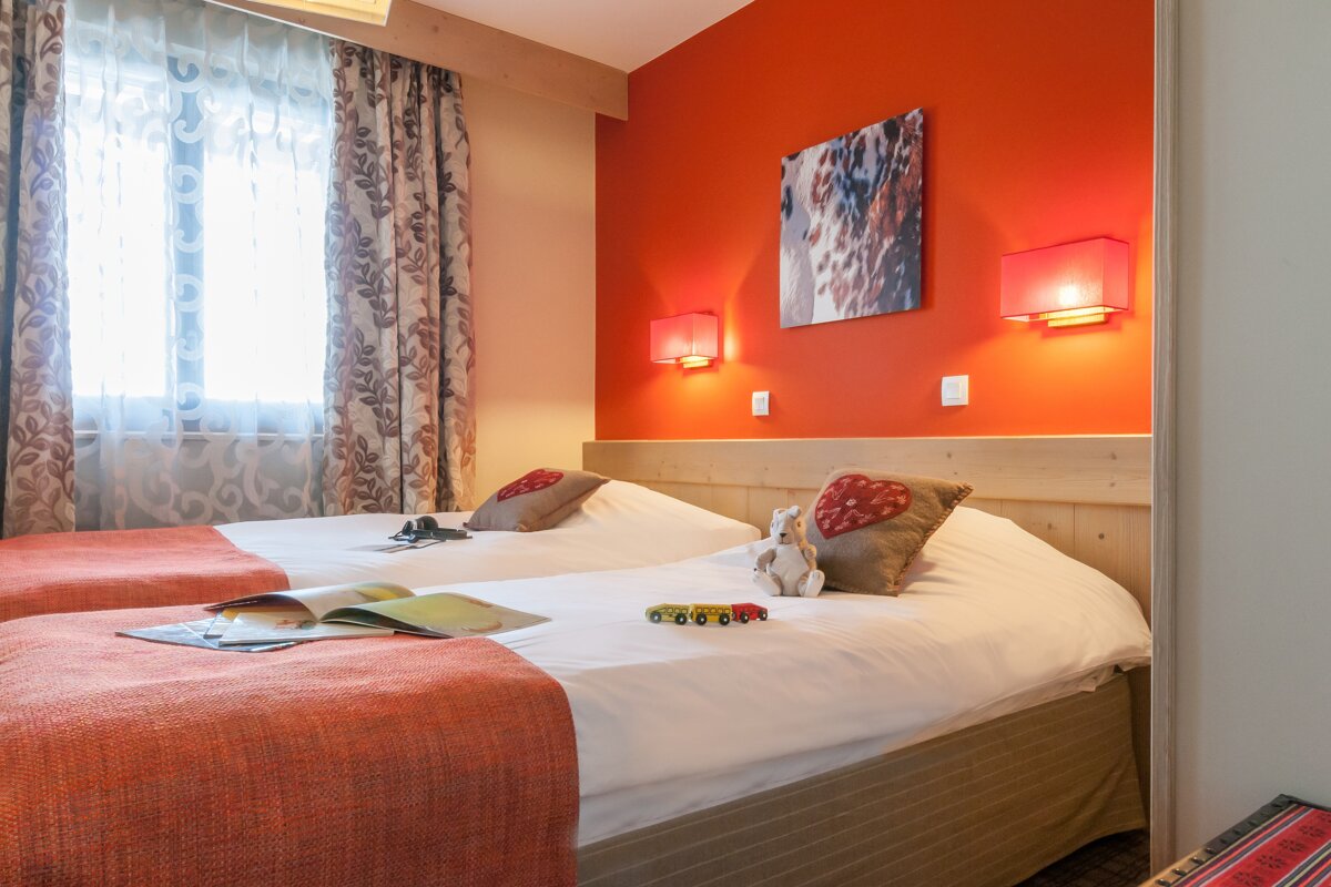 A bedroom with two beds and an orange wall