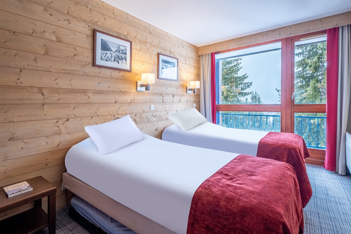 A hotel room with two beds and a large window