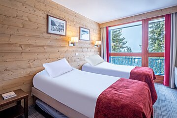 A hotel room with two beds and a large window