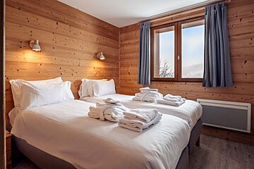 A bedroom with two twin beds and a window