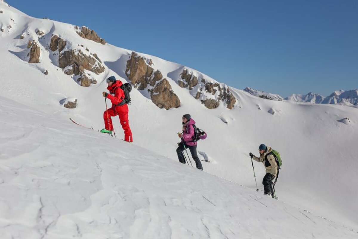 Three people skiing down a snow covered mountain