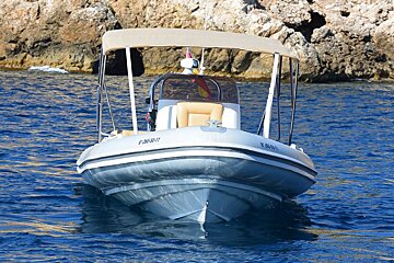 A boat with a canopy on top of it has a license plate that starts with t