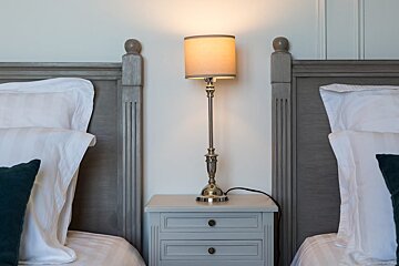 A bedroom with two beds and a nightstand with a lamp on it