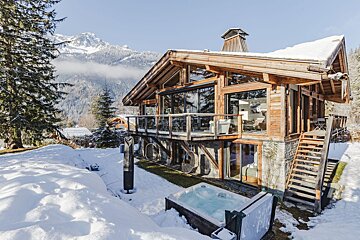 A large wooden house with a hot tub in front of it